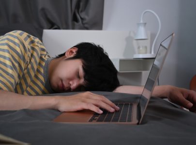 person sleeping with laptop on the bed